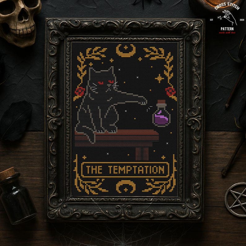 May include: Cross-stitch pattern in a black ornate frame. The design features a black cat with red eyes, reaching for a purple potion bottle. The text "THE TEMPTATION" is displayed in gold. The overall theme is gothic and witchy.