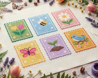 Pode incluir: Seis desenhos de ponto cruz com tema primaveril. Cada desenho, emoldurado com uma borda ondulada, mostra uma abelha, uma borboleta, uma flor, um pássaro, um broto e tulipas. Os desenhos estão em um fundo de linho neutro.