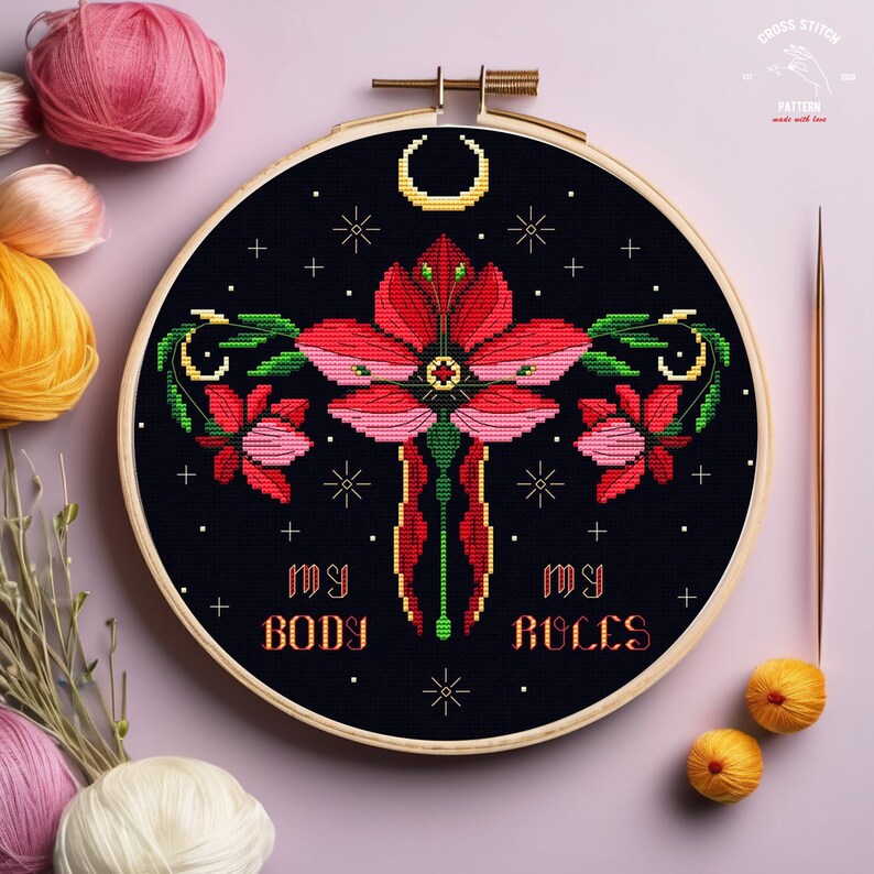 Puede incluir: Arte de bordado en aro con un dise&ntilde;o de flores rojas y rosas, una luna creciente y el texto "My Body My Rules" sobre un fondo negro.