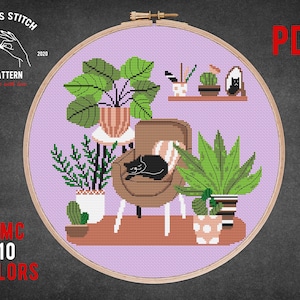 Puede incluir: Patrón de punto de cruz con un gato durmiendo en una silla rodeado de plantas. El patrón está en un aro morado con el texto "Cross Stitch" y "PDF" en la imagen.
