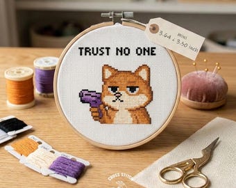 Pode incluir: Um bastidor de bordado em ponto cruz com o texto "TRUST NO ONE" e um cão Shiba Inu pixelizado segurando uma arma roxa. O bastidor tem 9,25 x 8,89 cm. Outros itens incluem carretéis de linha, linha de bordar e tesouras douradas.