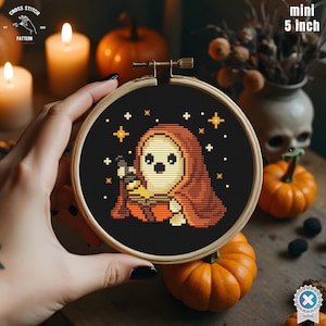 Puede incluir: Mini bordado de punto de cruz de 12,7 cm en un aro de madera. El diseño presenta un lindo personaje fantasma con una capa con capucha, sosteniendo una canasta de truco o trato. El fondo es negro con acentos de estrellas, perfecto para Halloween.