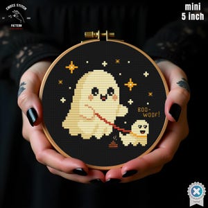 Può includere: Un telaio da ricamo a punto croce di 12,7 cm di diametro. Il disegno presenta un fantasma e un cane su sfondo nero, con la scritta "BOO-WOOF!" e dettagli a stella. Tema di Halloween.