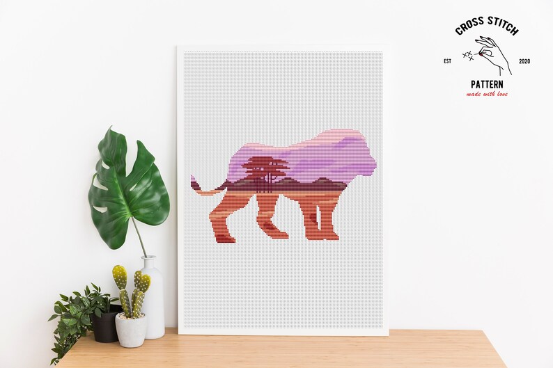 May include: Cross stitch pattern of a lion silhouette with a sunset landscape inside. The lion is facing right and the landscape is a purple and orange sunset with trees.