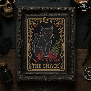 May include: Cross-stitch pattern featuring a black cat with red eyes, sitting on a red rose, framed in a decorative black frame. The text "THE CHAOS" is at the bottom. The frame is surrounded by gothic-themed objects.