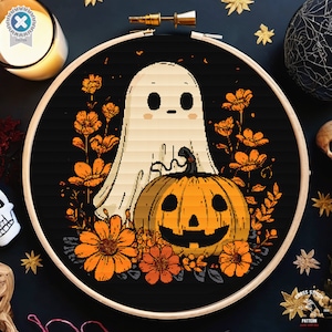 May include: A cross-stitch design showing a ghost and a carved pumpkin with orange flowers on a black backdrop, framed in a wooden hoop. Ideal for Halloween crafting and home decoration.