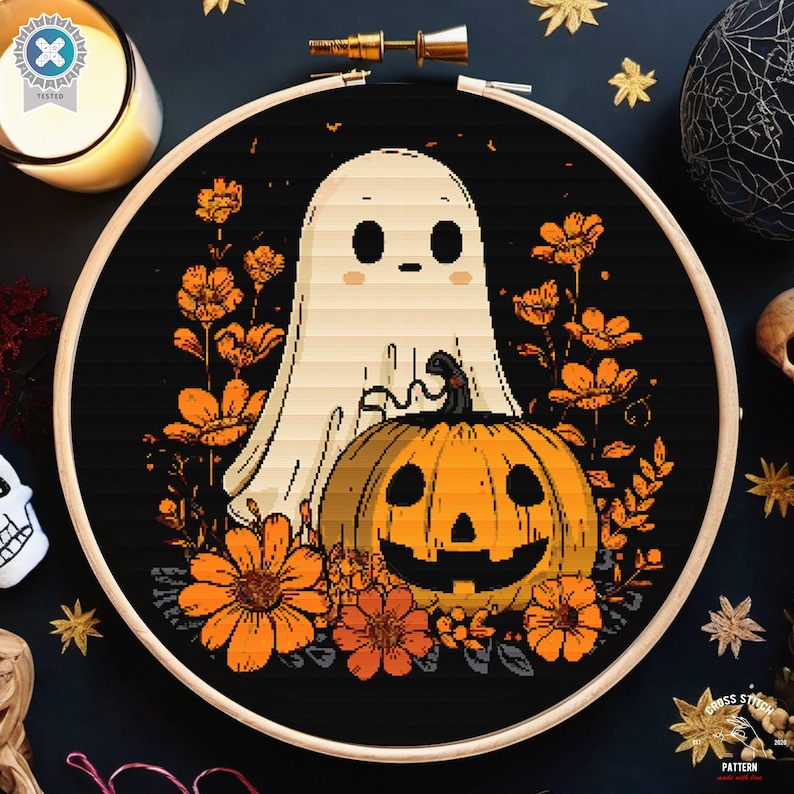May include: A cross-stitch design showing a ghost and a carved pumpkin with orange flowers on a black backdrop, framed in a wooden hoop. Ideal for Halloween crafting and home decoration.