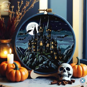 May include: A cross-stitch embroidery of a castle under a full moon, surrounded by bats, set in a blue hoop. The scene is decorated with pumpkins, a skull, and a lit candle, creating a Halloween theme.