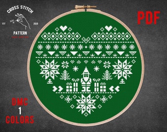 May include: A green cross stitch pattern in the shape of a heart with a white Christmas design. The design includes a snowman, snowflakes, trees, and presents. The pattern is in a wooden embroidery hoop. The text "PDF" is in the upper right corner of the image. The text "DMC 1 COLORS" is in the lower left corner of the image.