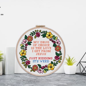 Puede incluir: Un patr&oacute;n de punto de cruz con un dise&ntilde;o de corona de flores. El texto dice "Mi droga de elecci&oacute;n es el amor que recibo de Jes&uacute;s. Es broma, es hierba."