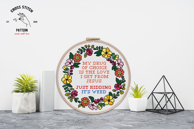 Puede incluir: Un patr&oacute;n de punto de cruz con un dise&ntilde;o de corona de flores. El texto dice "Mi droga de elecci&oacute;n es el amor que recibo de Jes&uacute;s. Es broma, es hierba."