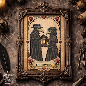 May include: Cross-stitch art in a decorative frame. The artwork depicts two figures in plague doctor attire holding a lantern, with the text "THE LOVERS" below. The frame is ornate, with a dark brown finish, and the background is a neutral tone.