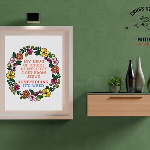 Puede incluir: Patr&oacute;n de punto de cruz con una corona de flores y el texto "My drug of choice is the love I get from Jesus. Just kidding, it's weed."