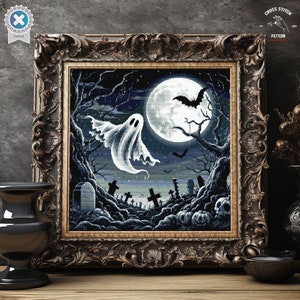 May include: A cross stitch pattern featuring a spooky Halloween scene with a white ghost flying in front of a full moon, bats, and a graveyard. The pattern is framed in a dark wood frame.