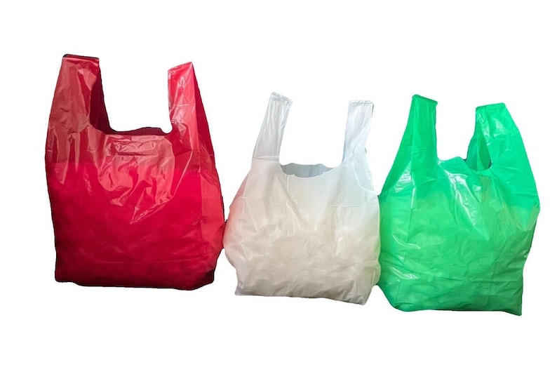 May include: Three plastic shopping bags, one red, one white, and one green, are arranged in a row against a white background.