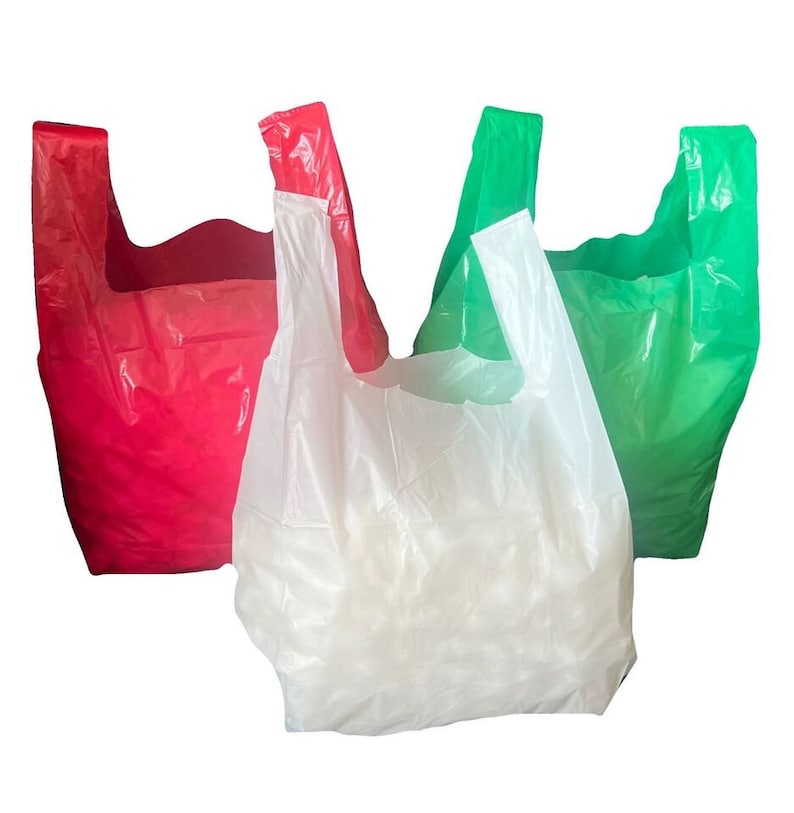 May include: Three plastic shopping bags, one red, one green, and one white. The bags are all folded and stacked on top of each other.