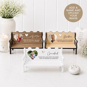 May include: Three wooden bench-style photo holders, two in brown and one in white. Each has a heart-shaped photo space and the inscription "Those we love don't go away, they sit beside us everyday." Personalised with names.