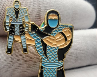 May include: A gold-colored metal pin featuring a blue and black character holding a smaller version of itself. The character is wearing a blue mask and has a black belt.