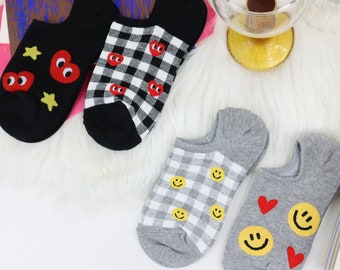 May include: Four pairs of ankle socks with different patterns. One pair is black with red hearts and stars. Another pair is black and white checkered with red hearts. The third pair is gray and white checkered with yellow smiley faces. The last pair is gray with yellow smiley faces and red hearts.