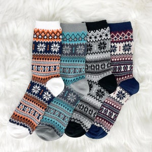 May include: Five pairs of winter socks with different patterns. The socks are in shades of blue, gray, red, white, and orange. The socks have a snowflake pattern.