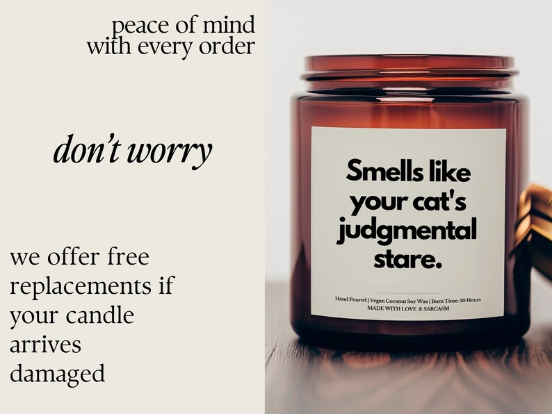 May include: A brown glass candle jar with a white label that reads "Smells like your cat's judgmental stare." The label also includes the text "Hand Poured | Vegan Coconut Soy Wax | Burn Time: 30 Hours | MADE WITH LOVE & SARCASM".