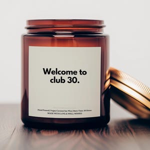 Peut inclure: Un bocal en verre brun contenant une bougie avec une étiquette blanche sur laquelle est inscrit "Welcome to club 30". La bougie est coulée à la main avec de la cire de soja et de noix de coco vegan et a une durée de combustion de 30 heures. Le bocal a un couvercle doré.