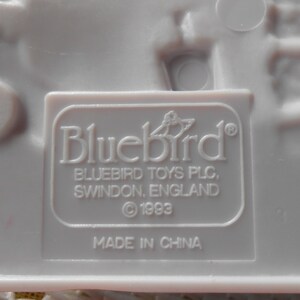 Puede incluir: Juguete de pl&aacute;stico blanco con una etiqueta de Bluebird Toys PLC. La etiqueta dice "Bluebird" con un logotipo de p&aacute;jaro, "Bluebird Toys PLC, Swindon, England", y "&copy; 1993". La etiqueta tambi&eacute;n dice "Hecho en China".