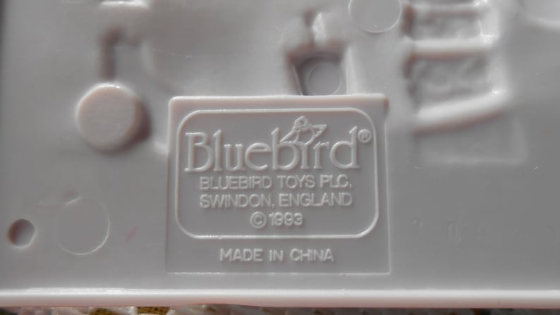 Puede incluir: Juguete de pl&aacute;stico blanco con una etiqueta de Bluebird Toys PLC. La etiqueta dice "Bluebird" con un logotipo de p&aacute;jaro, "Bluebird Toys PLC, Swindon, England", y "&copy; 1993". La etiqueta tambi&eacute;n dice "Hecho en China".