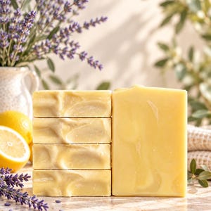 May include: A stack of four rectangular pale yellow soap bars positioned next to a single upright pale yellow soap bar. The soap has a smooth, solid texture with subtle swirls. The bars are light yellow in colour and have a clean, uniform appearance.
