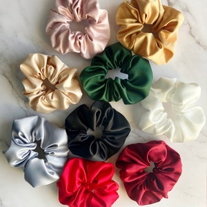 May include: Assortment of ten colorful satin scrunchies in various colors including red, green, black, white, gold, and light blue.
