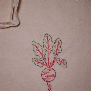 May include: A white canvas tote bag with a red and green embroidered beet design.