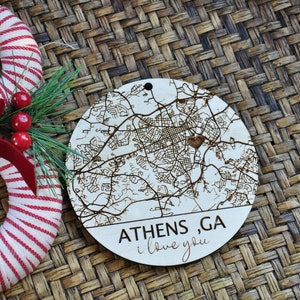 May include: A wooden Christmas ornament with a map of Athens, Georgia, and the text "Athens, GA I love you".