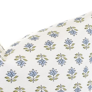 Puede incluir: Un coj&iacute;n blanco con un patr&oacute;n repetido de dise&ntilde;os florales azules y hojas verdes. El coj&iacute;n tiene un aspecto suave y texturizado, adecuado para la decoraci&oacute;n del hogar.