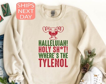 May include: A beige sweatshirt with a green moose graphic and the text "Hallelujah! Holy Sh*t! Where's the Tylenol"