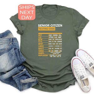 Peut inclure: Un t-shirt vert avec le texte "Senior Citizen Texting Code" imprimé sur le devant. Le texte est en blanc et le code est en jaune. Le code comprend des abréviations et leurs significations, telles que BFF, LOL, BTW, TTYL, BYOT, LMDO, WAITT, OMS, GGBPL et ROFLACGU.