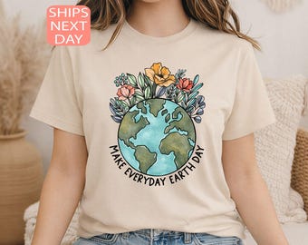 May include: Beige t-shirt featuring a colorful illustration of the Earth with flowers and the text "Make Everyday Earth Day." The design includes a globe with blue oceans and green continents, surrounded by various flowers.