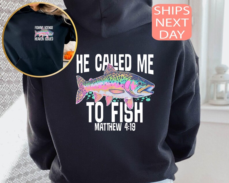 Peut inclure: Sweat &agrave; capuche noir avec un motif de poisson color&eacute; et le texte "HE CALLED ME TO FISH MATTHEW 4:19." Une petite image en haut &agrave; gauche montre une licence de p&ecirc;che avec le texte "FISHING LICENSE HEAVEN ISSUED."