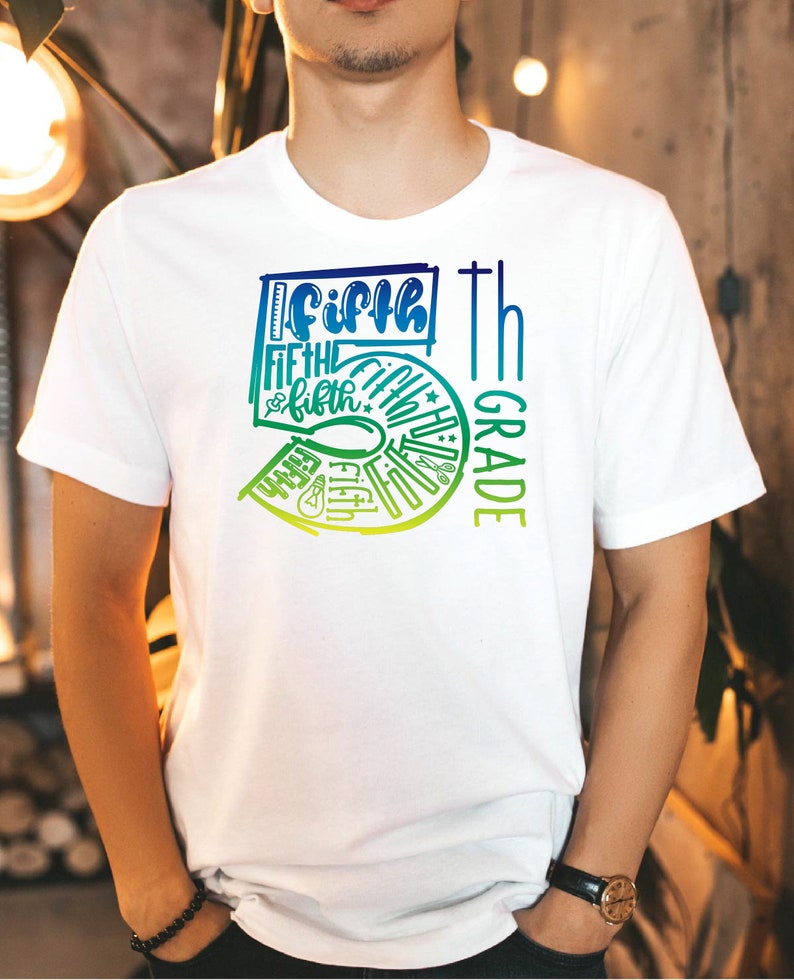 Pu&ograve; includere: T-shirt bianca con un design grafico colorato. Il design presenta le parole "Fifth Grade" in un gradiente di blu e verde, insieme a icone scolastiche. La maglietta &egrave; uno stile girocollo.