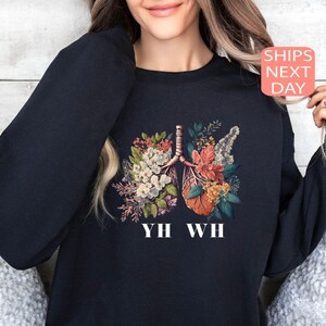 May include: Black sweatshirt with a floral print of lungs and the text "YH WH".