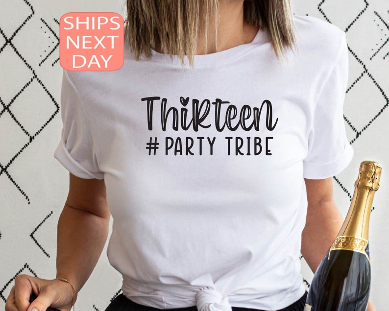 May include: White t-shirt with the text "Thirteen #Party Tribe" in black lettering. A small heart symbol is above the word "Thirteen".