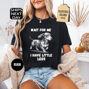 May include: Black t-shirt with a dachshund illustration and the text "WAIT FOR ME I HAVE LITTLE LEGS". The shirt also has the text "BLACK" and a tag that says "COMFORT COLORS 1717".