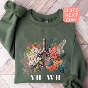 May include: Green sweatshirt with a floral print of a pair of lungs and the text "YH WH".