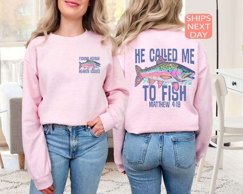 Peut inclure: Sweat-shirt rose clair avec un motif de poisson color&eacute; et le texte "FISHING LICENSE HEAVEN ISSUED" sur le devant. Le dos pr&eacute;sente un motif de poisson plus grand et le texte "HE CALLED ME TO FISH MATTHEW 4:19".