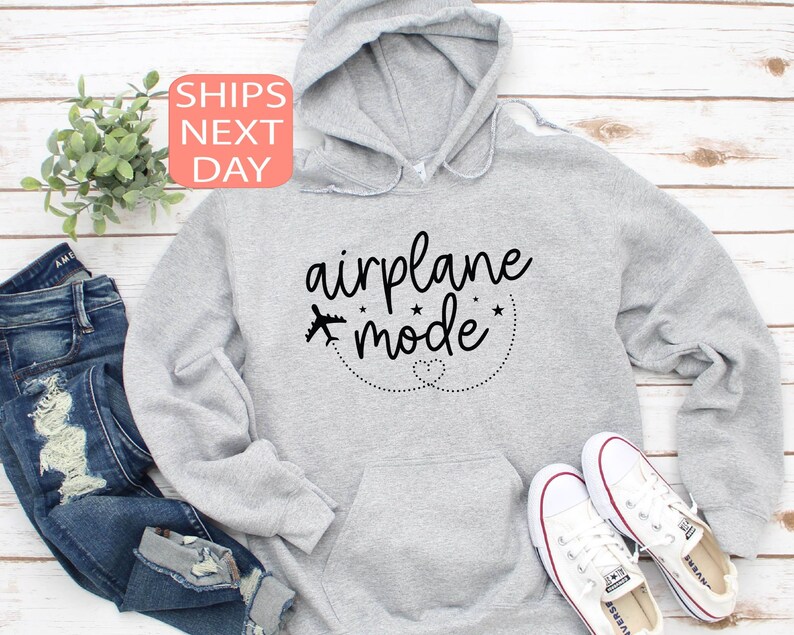 K&ouml;nnte beinhalten: Grauer Kapuzenpullover mit dem Text "airplane mode" in schwarzer Schrift. Der Text ist von einer gepunkteten Linie und zwei Sternen umgeben.