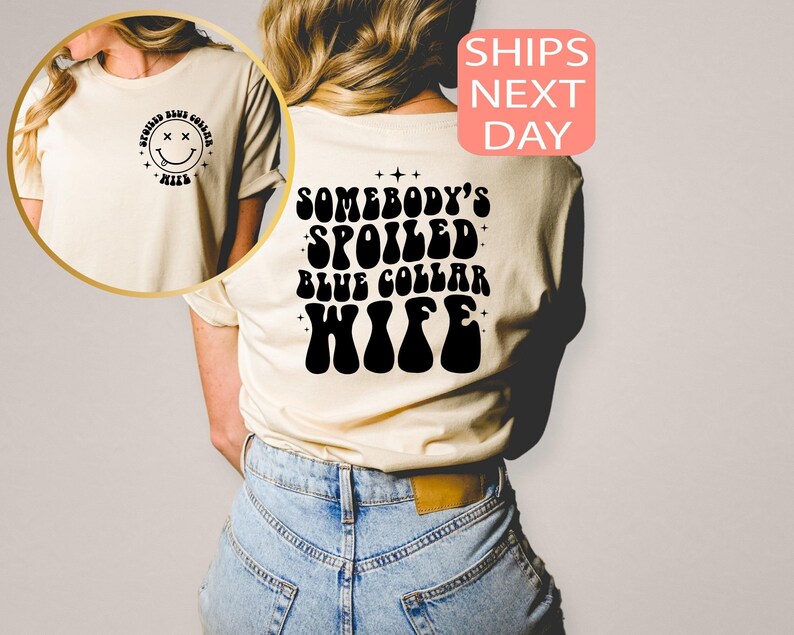 以下が含まれることがあります： 黒いレトロなフォントで「Somebody's Spoiled Blue Collar Wife」と書かれた白いTシャツです。