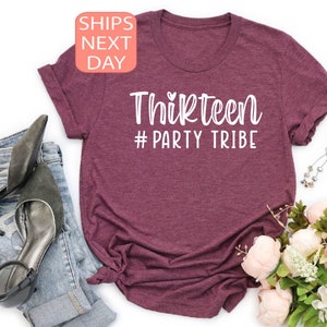 May include: A maroon t-shirt with white text that reads "Thirteen #Party Tribe".