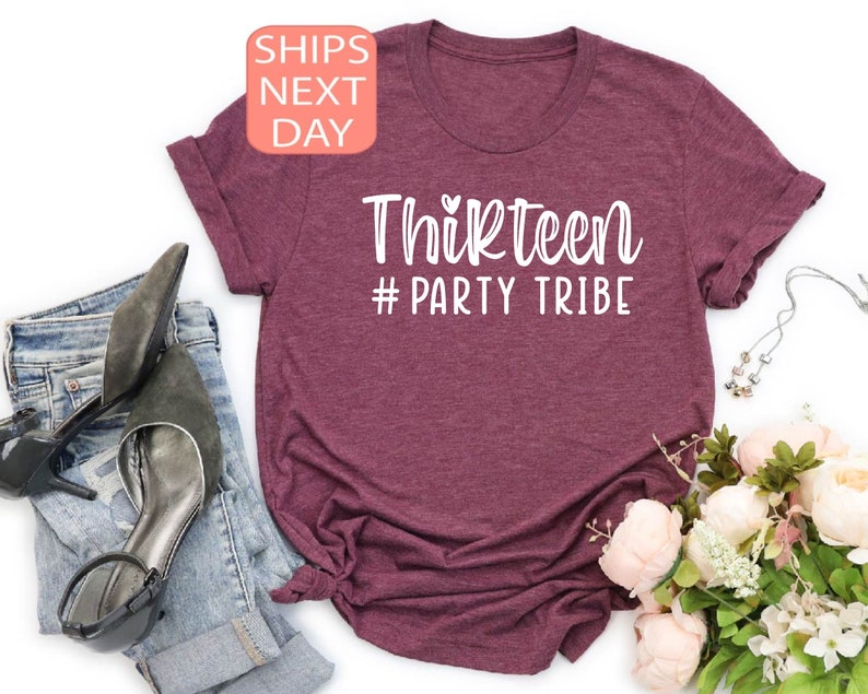 May include: A maroon t-shirt with white text that reads "Thirteen #Party Tribe".
