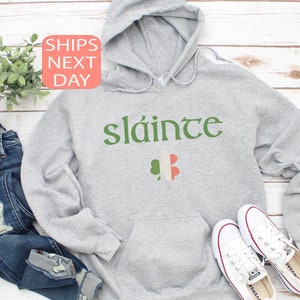 May include: Gray hooded sweatshirt with the Irish phrase "sl&aacute;inte" in green lettering and a shamrock with the Irish flag colors.