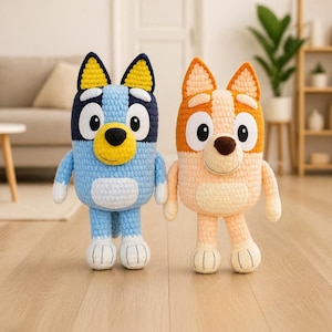 Puede incluir: Dos juguetes de peluche de ganchillo, uno azul y otro naranja, están uno al lado del otro. El juguete azul tiene un hocico y orejas amarillas, y el juguete naranja tiene un hocico marrón y orejas naranjas. Ambos tienen ojos grandes y redondos y están sobre un suelo de madera.