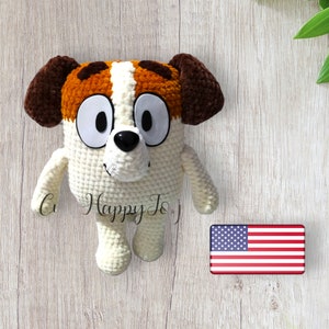 May include: A crocheted stuffed dog toy with brown ears, white fur, and orange and brown spots. The dog has large white eyes and a black nose.